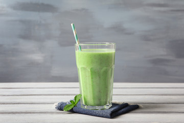 Glass with green milkshake on table