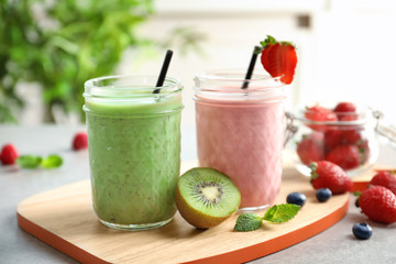 Glass jars with different milkshakes on wooden board