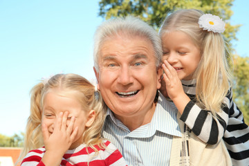 Elderly man with granddaughters in park