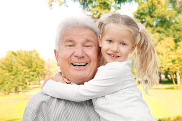 Cute little girl hugging grandfather in park