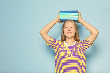 Cute teenager girl with books on color background