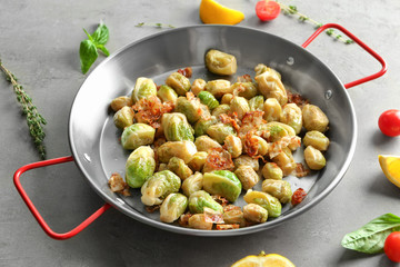 Frying pan with Brussels sprouts and bacon on table