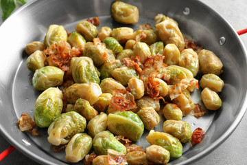 Frying pan with Brussels sprouts and bacon on table, closeup