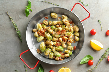 Frying pan with Brussels sprouts and bacon on table