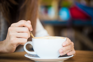 Women pouring with latte coffee on wood table