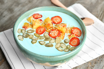 Bowl with yummy spirulina smoothie on wooden table. Healthy vegan food concept
