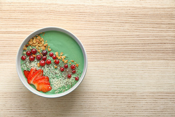 Bowl with yummy spirulina smoothie on wooden table. Healthy vegan food concept