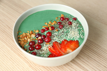 Bowl with yummy spirulina smoothie on wooden table. Healthy vegan food concept