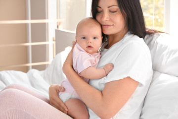 Young mother with baby on bed at home