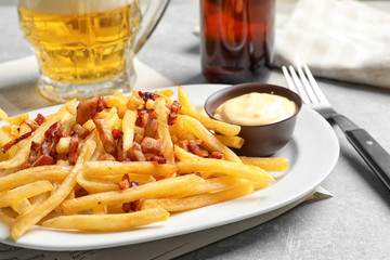 Plate with french fries and bacon on table