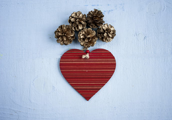 wooden heart toy decorated pinecone flat lay on wooden blue background.