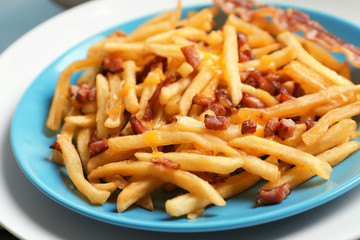 Plate with french fries and bacon on table, closeup