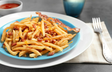 Plate with french fries and bacon on table