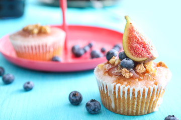 Delicious muffin with caramel sauce, blueberries and fig on table