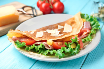 Plate with thin buckwheat pancake, bacon and vegetables on table