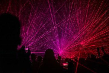 Silhouette of crowded people in light and sound performance concert