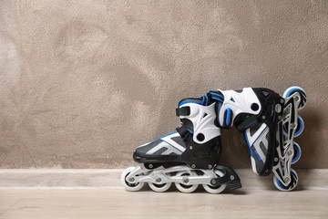 Pair of roller skates on floor against light wall