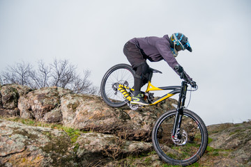 Fototapeta na wymiar Professional Cyclist Riding Mountain Bike Down the Rocky Hill. Extreme Sport and Enduro Biking Concept.