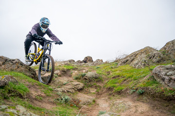 Professional Cyclist Riding Mountain Bike Down the Rocky Hill. Extreme Sport and Enduro Biking Concept.