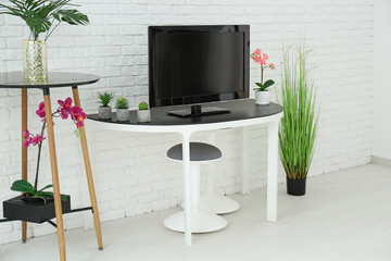 Modern TV on stand against brick wall