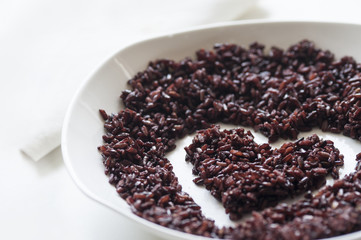 Thai jasmine black rice in heart shape on white ceramic plate
