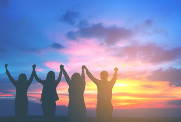 Silhouette of happy business team hold hands up in sunset sky background, business teamwork, business achievement conceptual