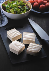 Feta cheese with greek salad and tomatoes on the brown wood table 