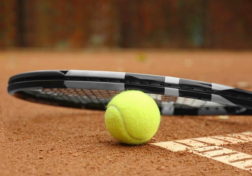 Tennis racket and ball on court, closeup