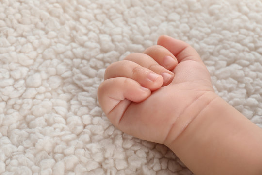 Baby hand on light plaid, closeup