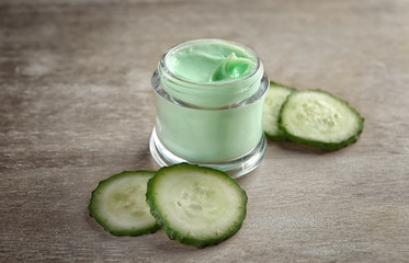 Jar of body cream with sliced cucumber on table