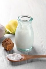 Bottle and spoon of body cream on table
