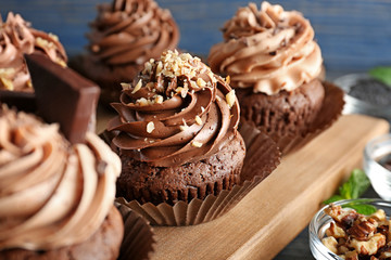 Tasty chocolate cupcakes on wooden board, closeup