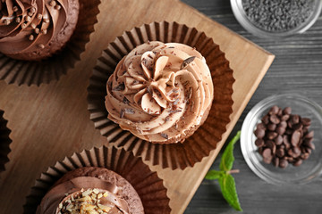 Tasty chocolate cupcakes on wooden board