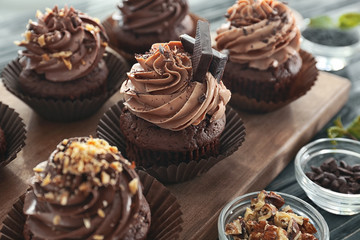 Tasty chocolate cupcakes on wooden board