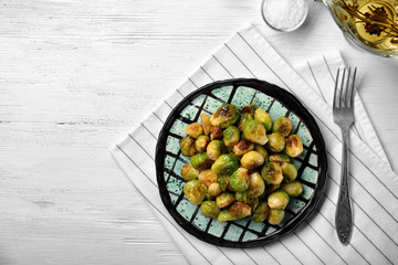 Plate with roasted Brussels sprouts on wooden table