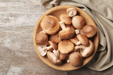 Bowl with raw shiitake mushrooms on wooden table