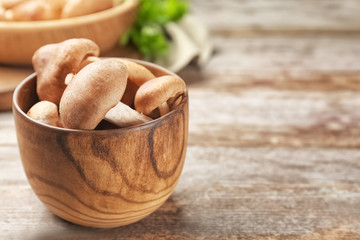 Bowl with raw shiitake mushrooms on wooden table, closeup