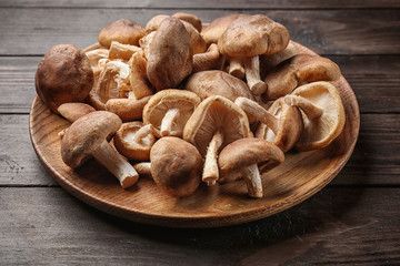 Dish with raw shiitake mushrooms on wooden table