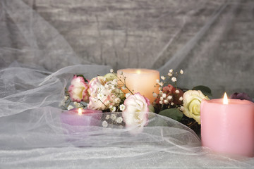 Composition with burning candles and flowers on light background