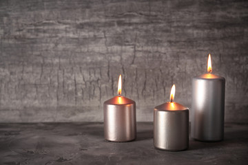 Silver burning candles on light background
