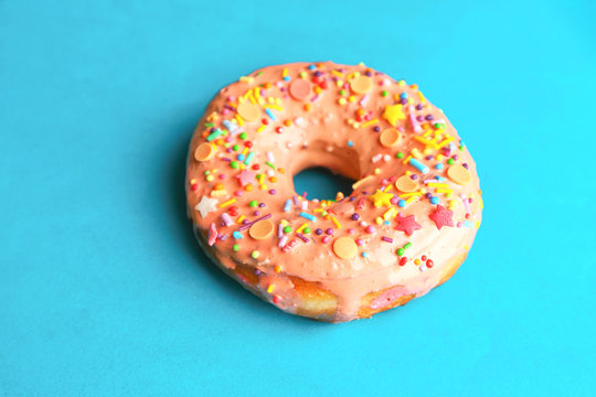 Tasty glazed donut on color background