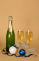 Glasses of champagne decorated with silver ribbon, new year toys and serpentine, on beige