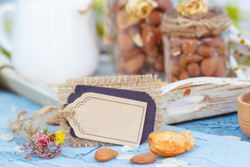 Almonds in the glass, jar with milk on the wooden tray and decorative tag