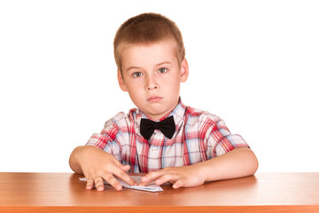 Naklejka premium Small boy in plaid shirt folds sheet of paper, at table, isolated on white
