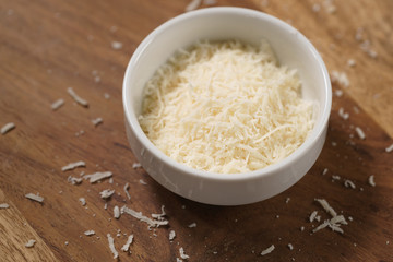 grated aged italian parmesan cheese in white bowl on table