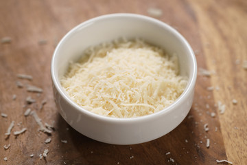 grated aged italian parmesan cheese in white bowl on table