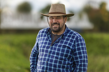 bearded brutal macho in cowboy hat ulybayutsya and happy life, full of positivity and optimism and is confident in the future