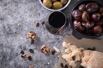 Grilled chestnuts cheese,olives and a glass of wine on a dark background. food concept composition