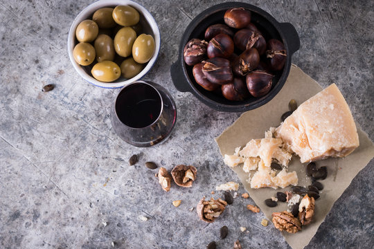 Grilled chestnuts cheese,olives and a glass of wine on a dark background. food concept composition