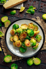 Homemade Roasted Brussel Sprouts with Parmesan cheese, lemon, Salt, Pepper on a old stone rustic table.